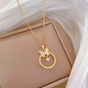 Detail of gold butterfly pendant with sparkling crystals on beige jewelry box