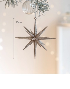 Dettaglio di una stella glitter oro champagne da 15 cm appesa al ramo di un albero di Natale