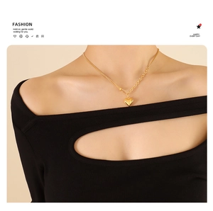 Detailed view of golden heart pendant necklace with layered chain and polished finish
