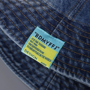 Deep blue denim bucket hat featuring contrast yellow stitching and embroidered patch detail