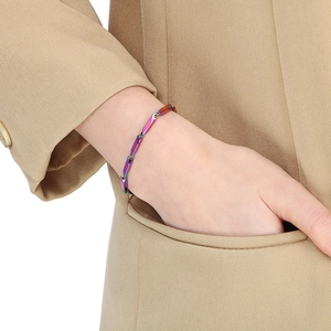 Close-up of rainbow stainless steel stick chain bracelet on a model's wrist with beige blazer