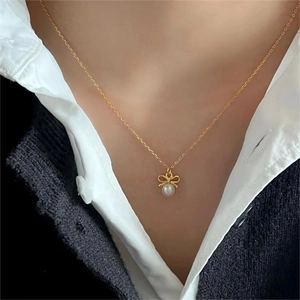 Chic 925 silver necklace featuring a golden bow and pearl pendant worn on a female neck