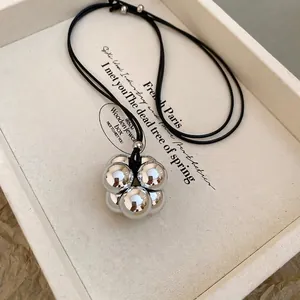 Dettaglio del ciondolo in argento con sei sfere lucide su una collana di cordino nero