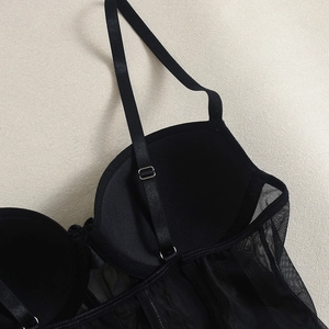 Detail of black mesh corset top showing adjustable straps and satin cup stitching