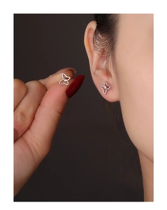 Detailed view of dainty S925 silver double-loop butterfly earrings on a model's ear