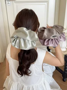 Detail of oversized satin scrunchies in green, brown and purple with silky texture