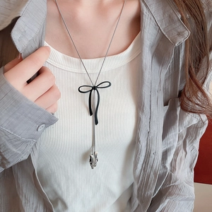 Detail of silver chain necklace featuring a black bow and metallic star pendant on model