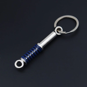 Detail of metal car shock absorber keychain with blue spring on a dark background