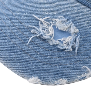 Macro detail of distressed denim baseball cap showing vintage frayed holes and stitching