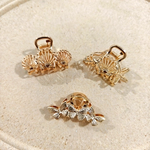 Detailed close-up of golden shell and butterfly hair clips on a textured background