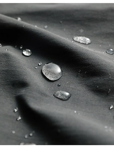 Macro shot of water droplets on dark grey water-resistant apron fabric texture
