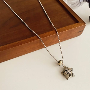Close-up of a star-shaped dalmatian stone pendant with a silver floral cross and crystal