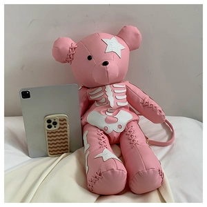 Detailed view of pink teddy bear backpack with star and bone patches on white bedding