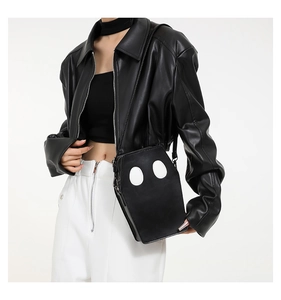 Detail of coffin-shaped crossbody bag made of textured faux leather with white oval patches