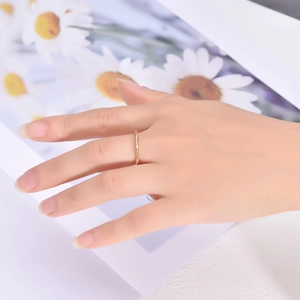 Minimalist 18K gold bamboo joint ring on model hand with elegant floral background
