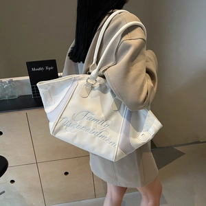 Large cream canvas bowling bag with embroidery and mesh panels shown on a model