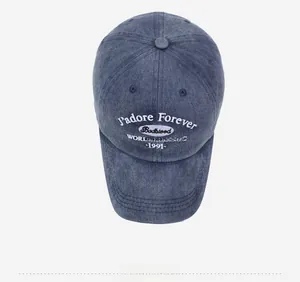 Detailed top view of a washed blue denim baseball cap with intricate white embroidery