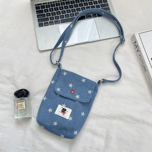 Flat lay van denim telefoontas met sterrenprint en cartoon patch op witte stof
