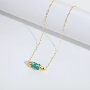 Close-up of golden cylindrical pendant with teal enamel inlay and cloud pattern engraving