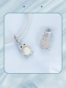 Macro detail of S925 silver owl pendant with luminous stone and green gem eyes