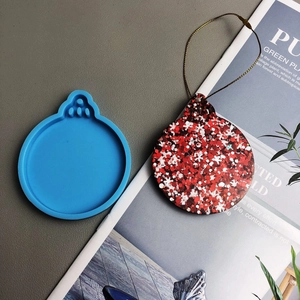 Detail of blue silicone Christmas mold and reindeer snowflake resin pendant on a magazine