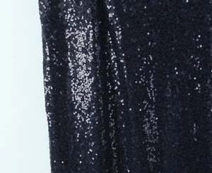 Detailed macro view of the shiny navy blue sequin fabric with reflective texture