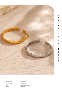 Detail of twisted rope bangles in gold and silver finish on a stone surface