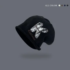 Slouchy black knit beanie with large K letter leather patch and silver rivets