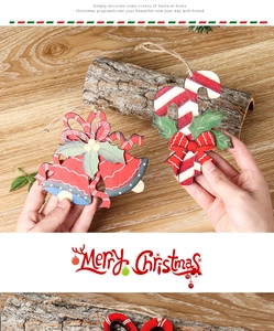 Hand holding a rustic wooden Christmas ornament with bell and holly on a wooden table