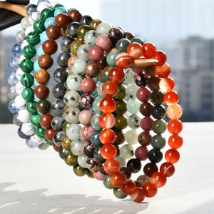 Close-up of diverse 8mm natural stone bracelets hanging on a wooden jewelry display stand