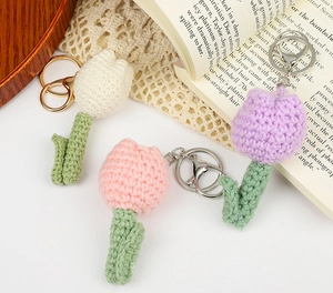 Detailed view of hand-knitted tulip keychains in white, pink and purple yarn textures