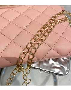 Detail of pink quilted handbag showing gold metal chain strap and luxury texture