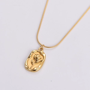 Detail of a vintage golden rectangle pendant with embossed tulip and wavy edge