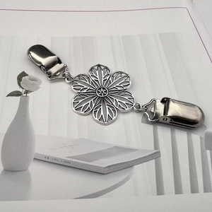 Détail macro d'un clip cardigan fleur argentée avec boucles bec de canard sur bureau