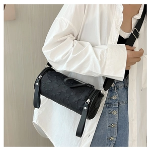 Detail of black cylindrical crossbody bag with bubble texture fabric and woven strap
