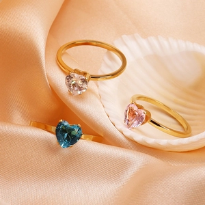 Detailed macro view of heart-shaped gemstone rings in white, pink, and blue on silk