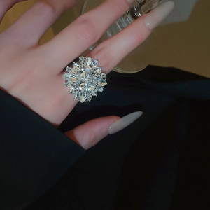 Macro close-up of a sparkling silver flower cluster ring with rhinestones on a hand