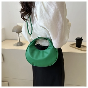 Detail shot of bright green crescent hobo bag worn over the shoulder by a model