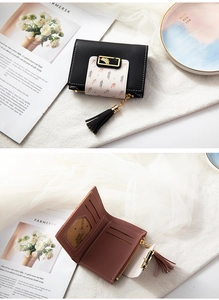 Close-up of a slim women's wallet with black leather, leaf pattern buckle, and black tassel
