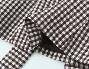 Detailed macro view of brown gingham fabric texture and durable stitching on a top