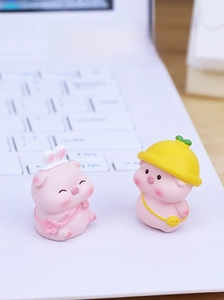 Close-up of two cute mini resin pig figurines on a laptop keyboard for desk decor