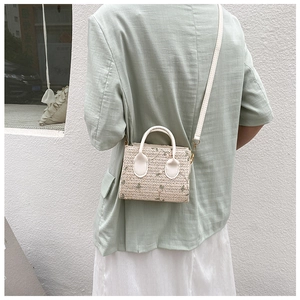 Detail of a straw crossbody bag with floral embroidery and white leather strap