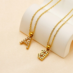 Close-up of gold initial pendants A and B with pearl inlay on white display stand