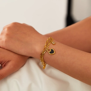 Double-layer gold heart bracelet with black shell pendant and cubic zirconia on wrist