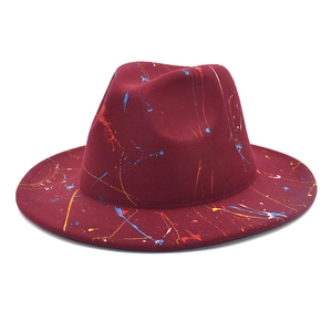 Gros plan du chapeau fedora en laine rouge foncé avec design artistique de taches de peinture