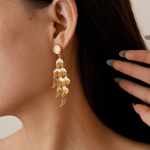 Detailed view of leaf-shaped gold tassel earrings with opal stones on a female model