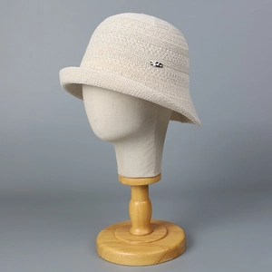 Detail of cream knit bucket hat with textured patterns and a small silver metal logo