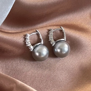 Detailed close-up of grey pearl earrings with pavé zircon setting on brown silk