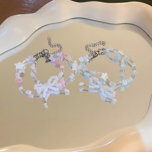 Double-layer handmade beaded bracelets with bow and star charms on a reflective surface