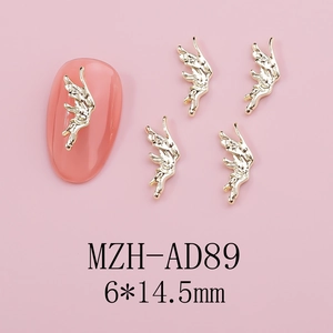 Macro detail of golden metal angel wing nail charms with hollow carving texture